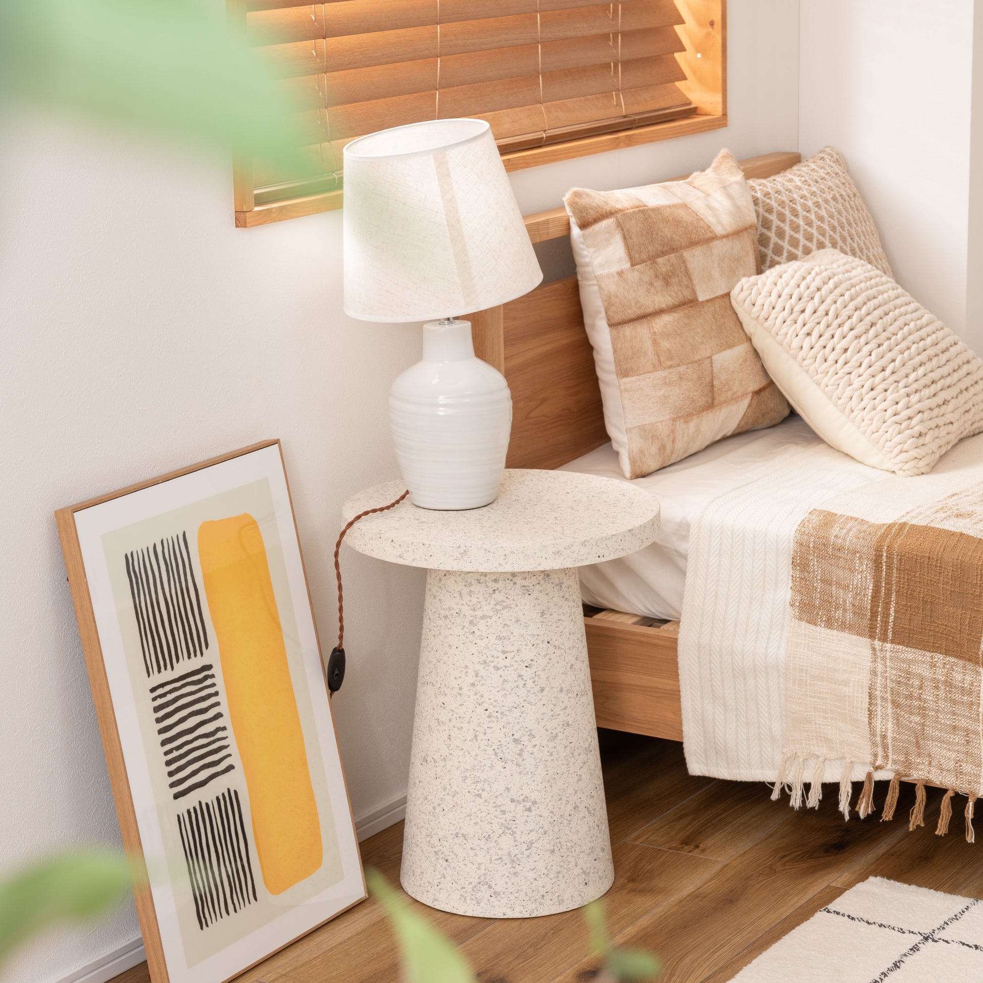 ベッド横にテラゾー柄ラウンドサイドテーブルが置いてある様子