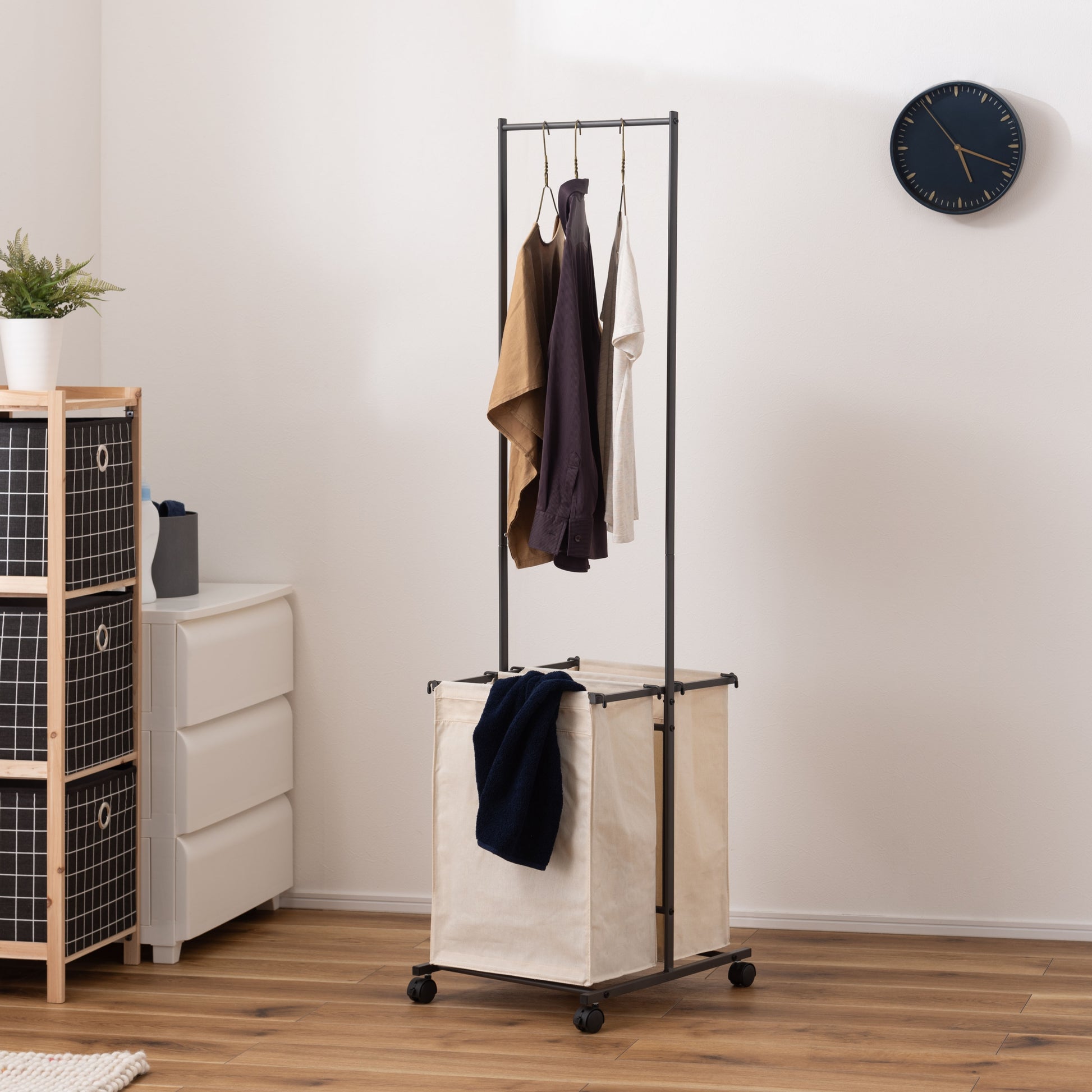 ダークグレーのスタイリッシュなスチールフレームの2つカゴ付きランドリーハンガーが部屋に置いてある写真