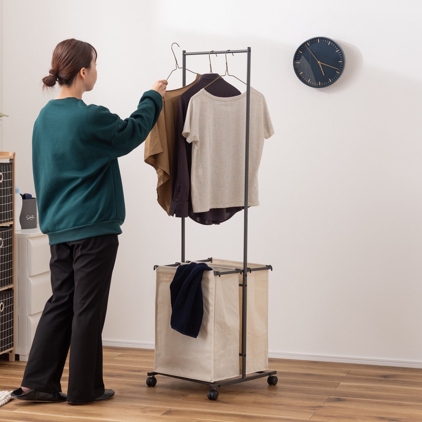 ダークグレーのスタイリッシュなスチールフレームの2つカゴ付きランドリーハンガーが部屋に置いてある写真