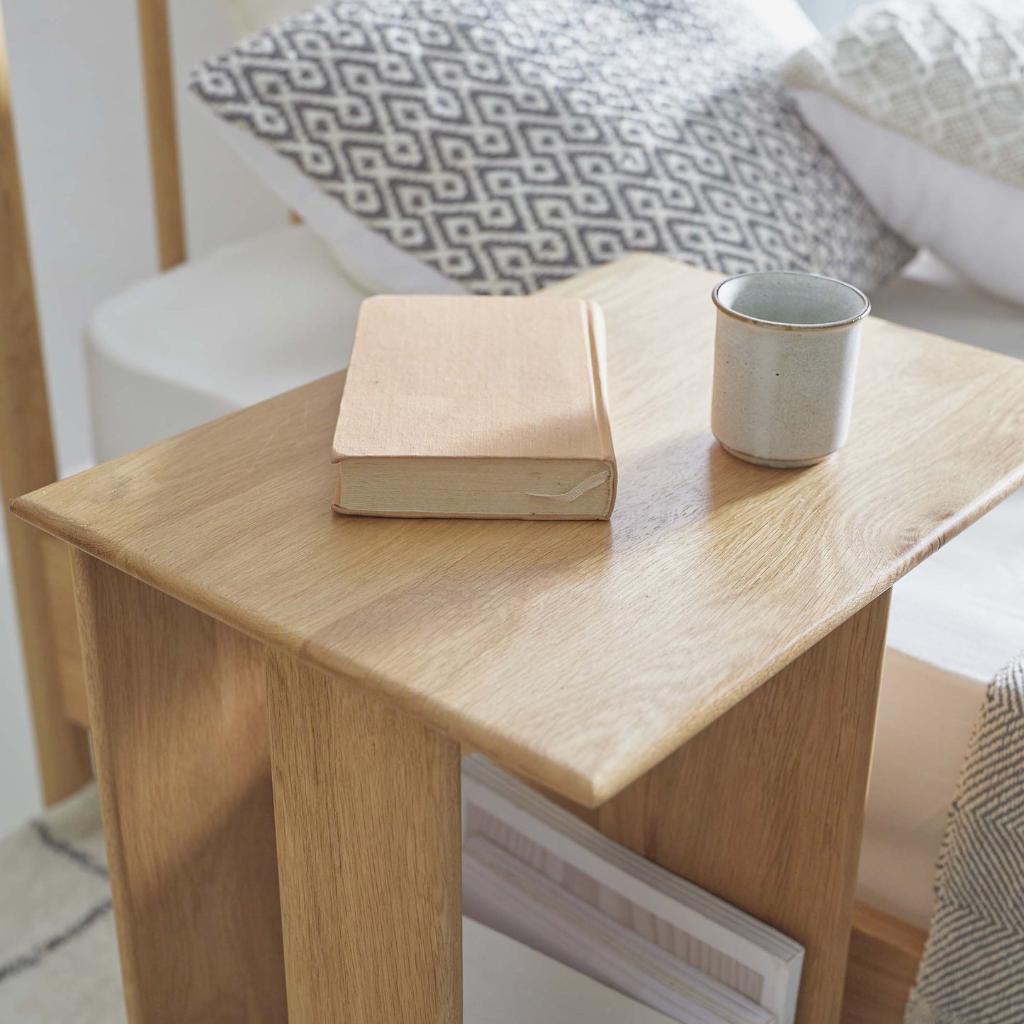 ラック付きオークサイドテーブルの天板にコップと本が置かれている様子