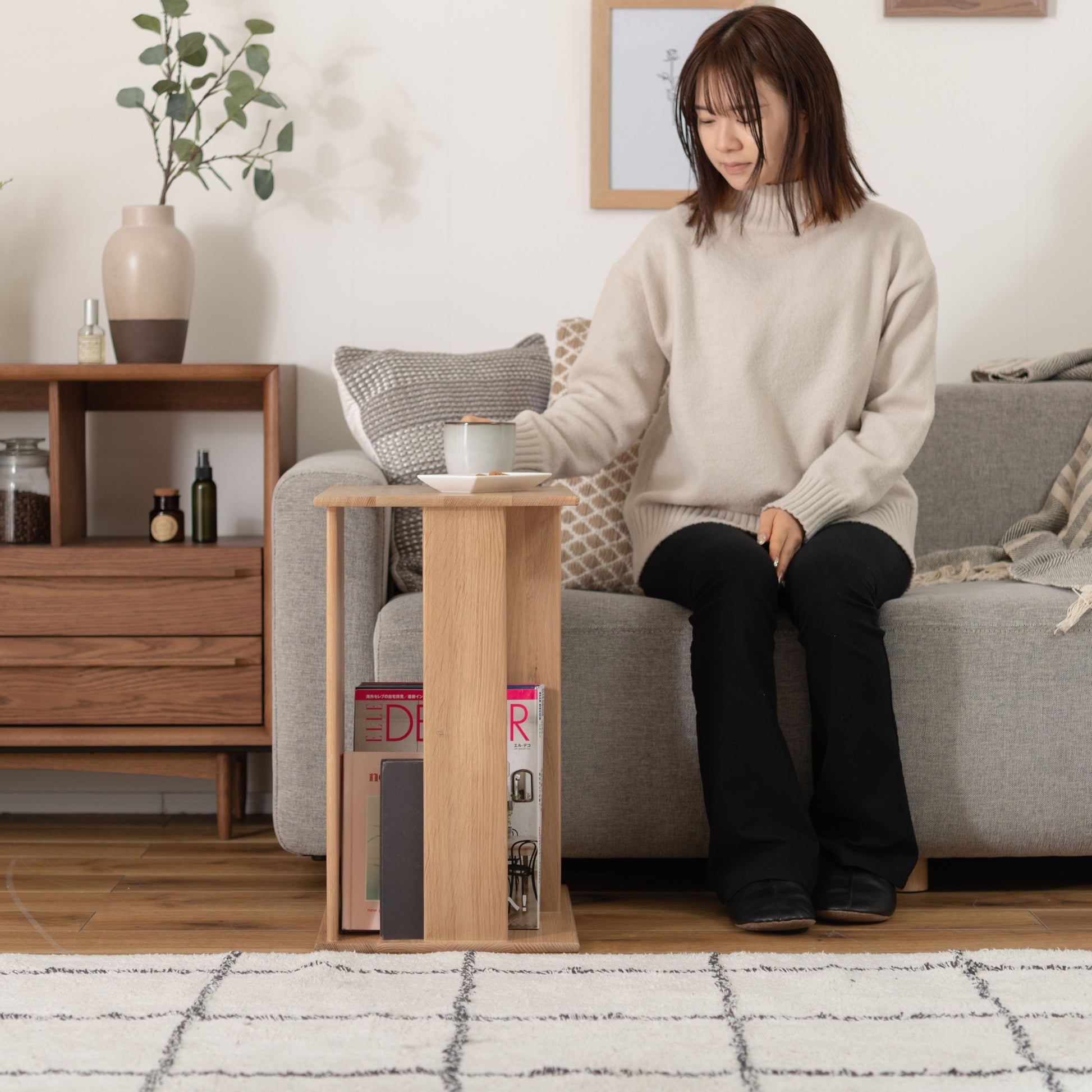 ラック付きオークサイドテーブルをソファ前に置きお茶を飲んでいる様子