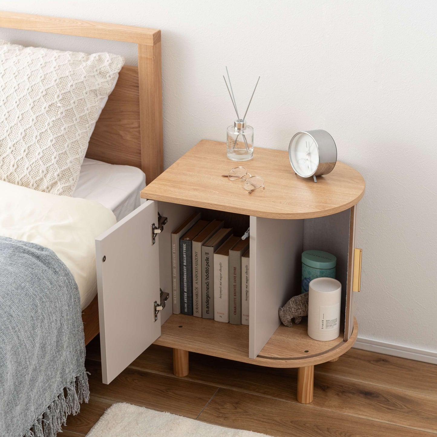 ゴールドとグレージュのモダンなデザインのサイドキャビネットがベッドサイドに置いてある部屋