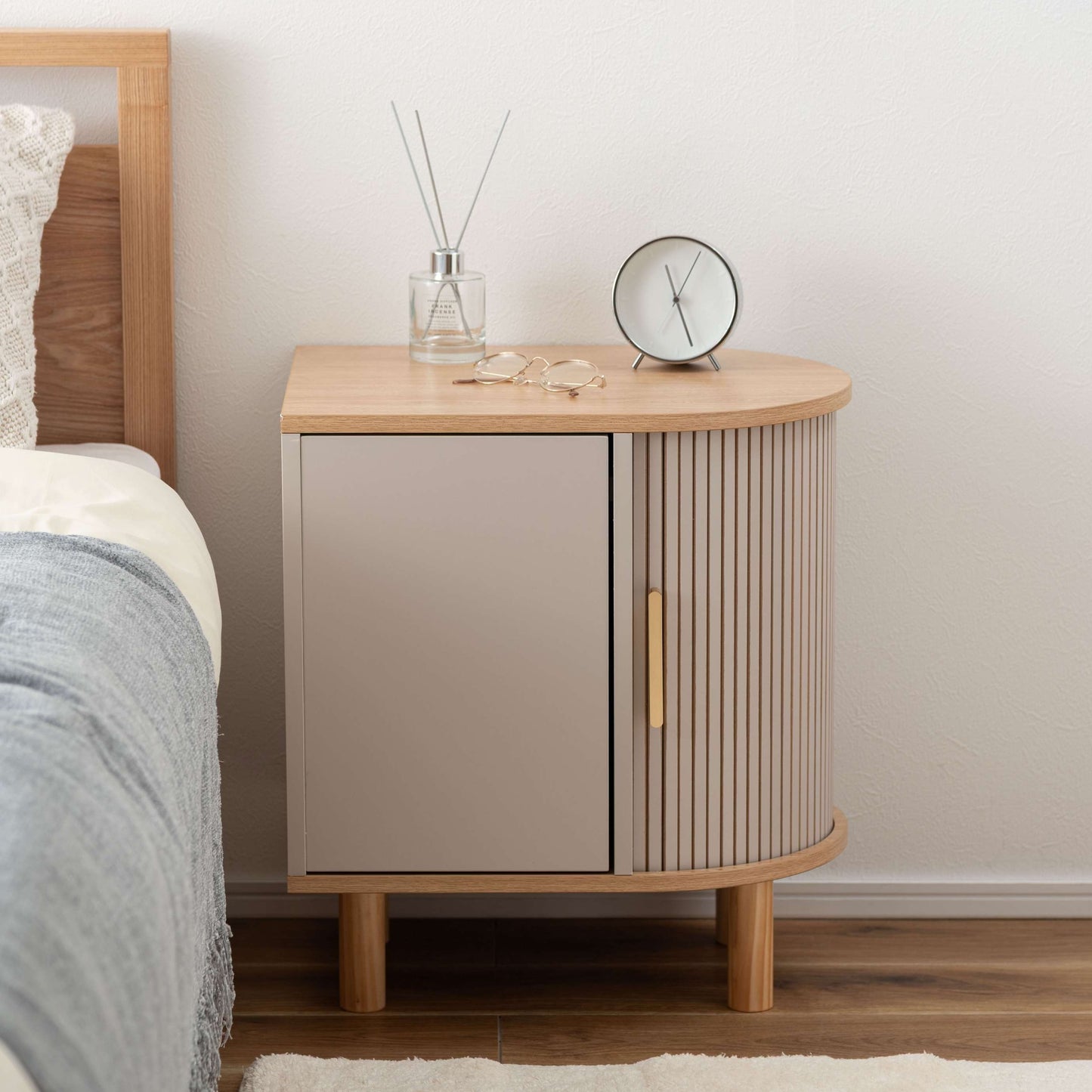 ゴールドとグレージュのモダンなデザインのサイドキャビネットがベッドサイドに置いてある部屋