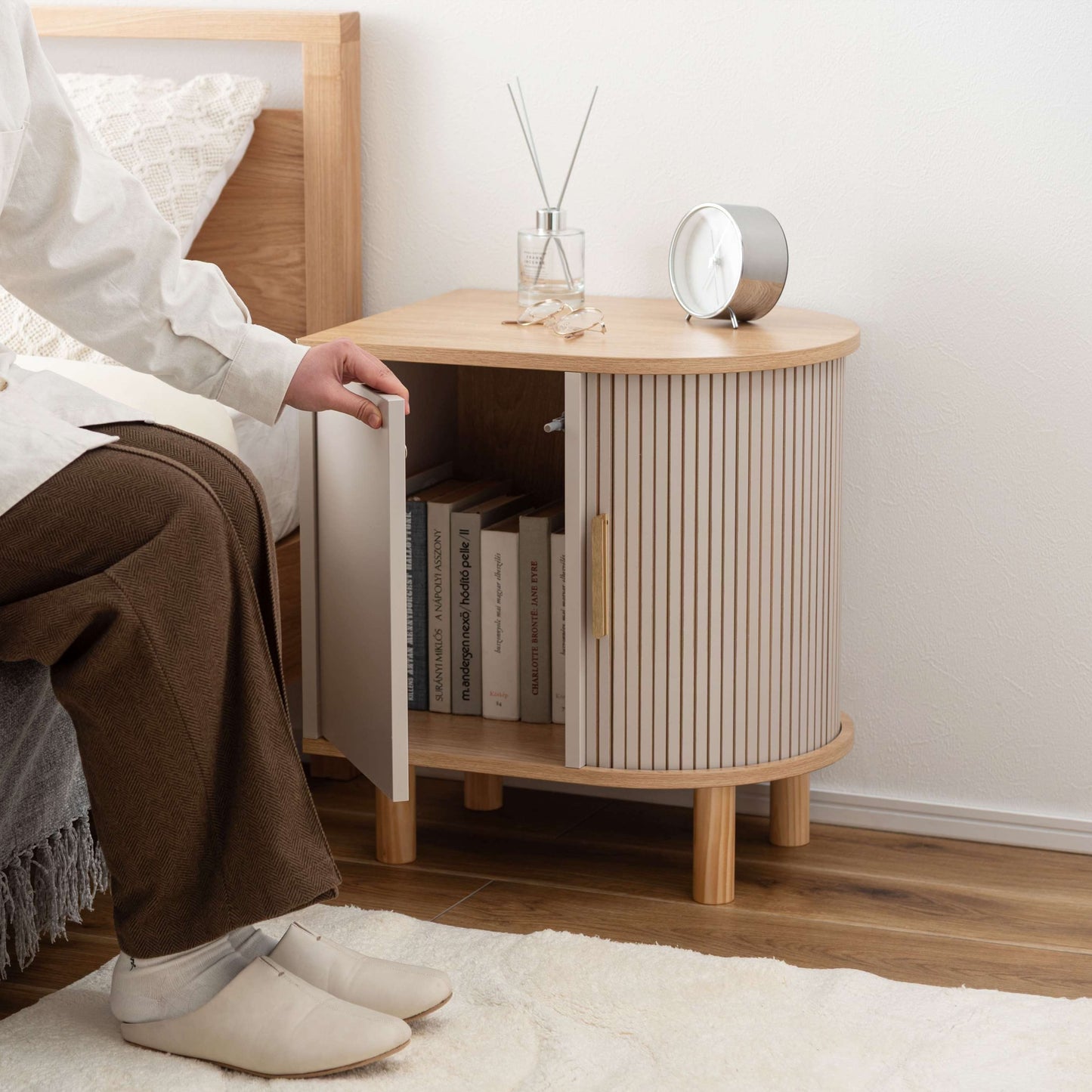 ゴールドとグレージュのモダンなデザインのサイドキャビネットがベッドサイドに置いてある部屋