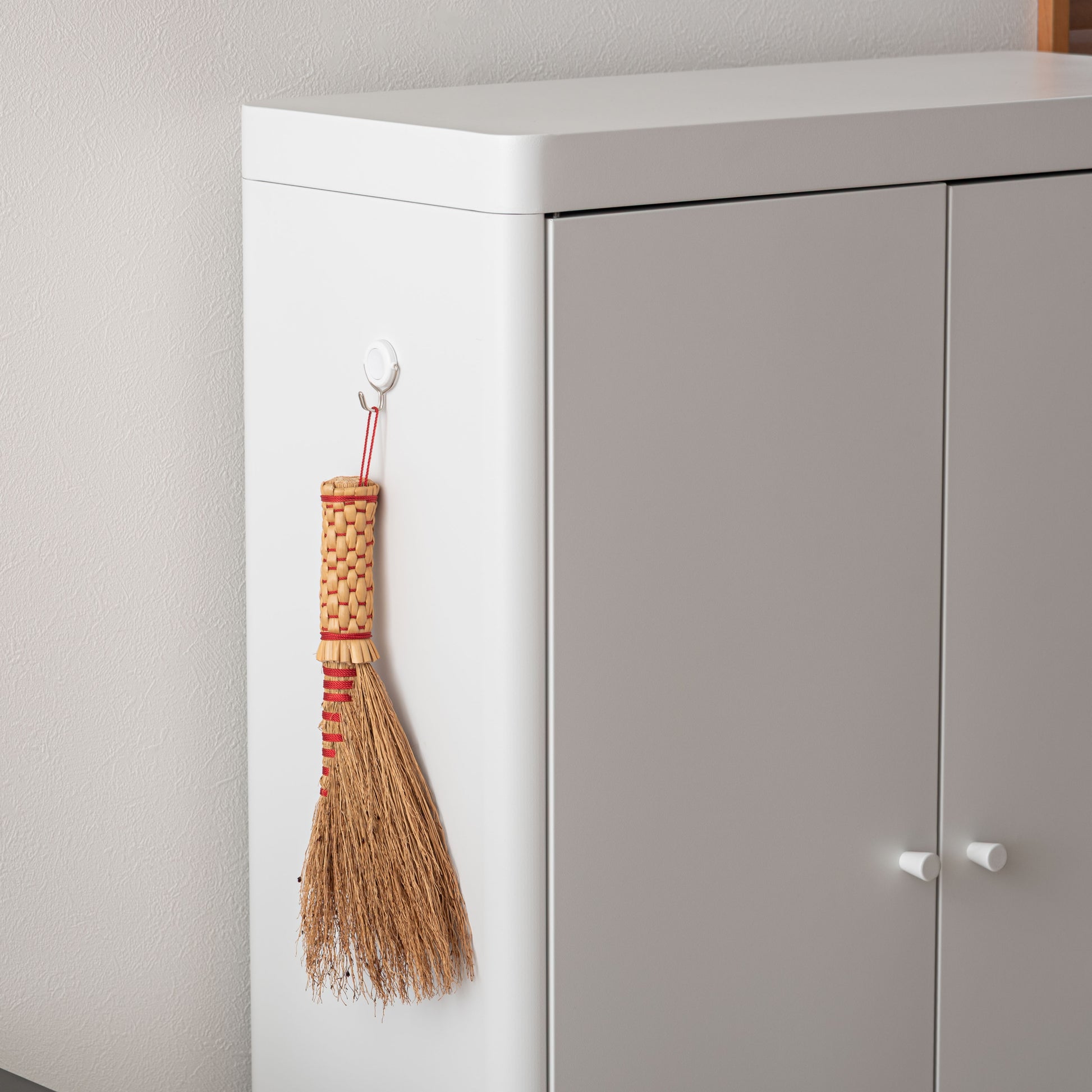 白のスチール製のシンプルなキャビネット収納に磁石のフックを付けている様子