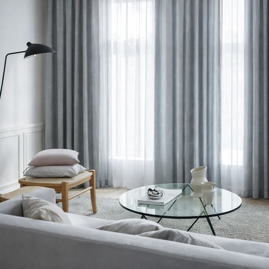 花びらの色のブルーのグラデーションで生地の動きと共に色の変化を楽しめるカーテンが部屋の窓にかかった写真