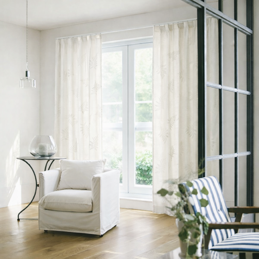 ベージュの繊細なリーフ柄の刺繍が目を引くやさしい表情のレースカーテンが窓にかかったリビング