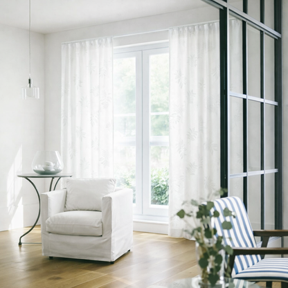 白の繊細なリーフ柄の刺繍が目を引くやさしい表情のレースカーテンが窓にかかったリビング