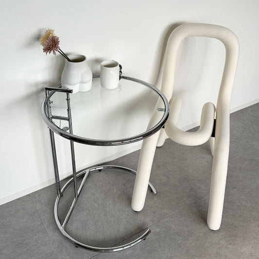 針金を曲げたようなユニークなデザインの白い椅子　お尻型の花瓶　白いコップ　丸いクリアサイドテーブル