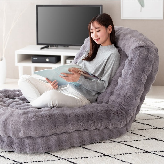 グレーのふわふわな生地のソファベッドに座って雑誌を読んでいる様子