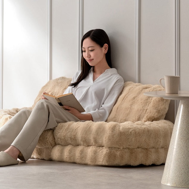 ベージュのふわふわな生地のソファベッドに座って本を読んでいる様子