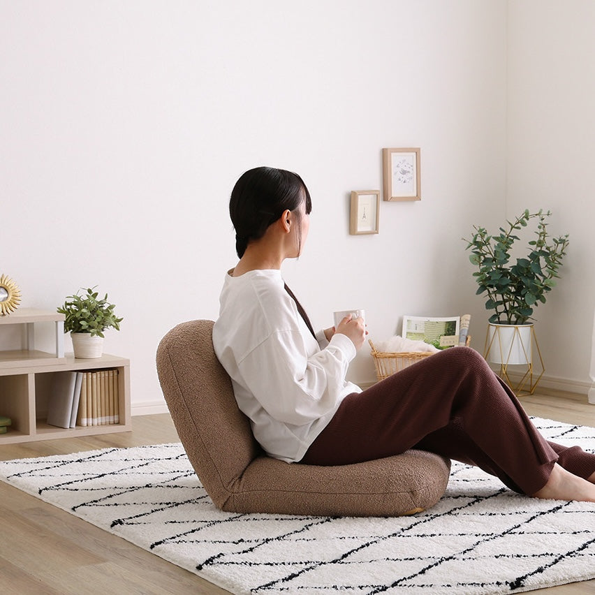 ブラウンのブークレ座椅子に腰掛けている様子