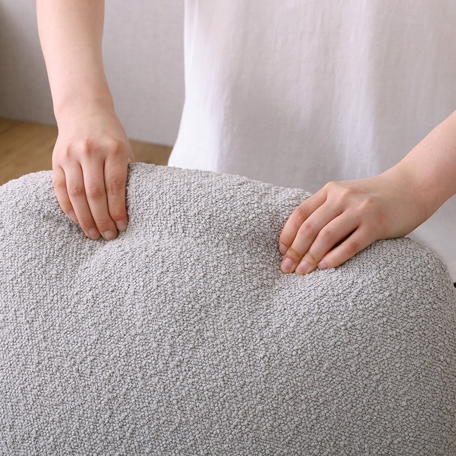 グレーのブークレ座椅子の背もたれを手で掴んでいる様子