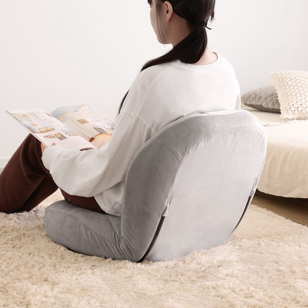 グレーのキルティングベロア座椅子に腰掛けて雑誌を読んでいる様子